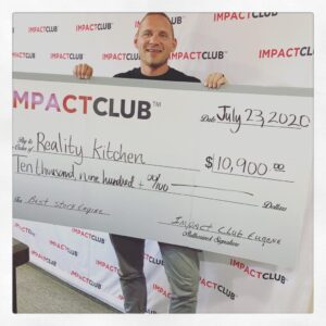 A man holding up a check for ten thousand, nine hundred dollars from Impact Club Eugene