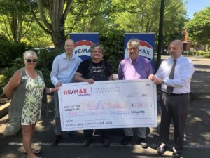 A group of people holding up a check for five thousand dollars from ReMax Integrity Foundation