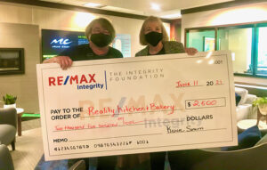 Two people holding a check for two thousand five hundred dollars from the ReMax Integrity Foundation